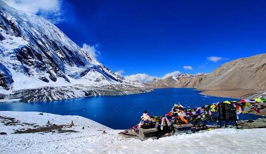 Tilicho Lake with Blue Waters and a glimpse of Tilicho Peak with colorful prayer flags.